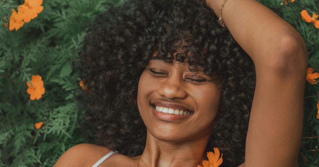 Smiling woman relaxing among orange flowers, illustrating the link between genetics and mood